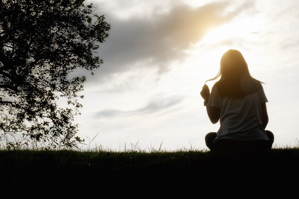 Sad And Depressed Woman Sitting Alone At The Field During Beautiful Sunset With Park Background. Selective Focus.